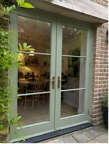 Sage timber French doors opening from a brick home